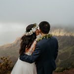 Bride kissing groom at mountain overlook in Kauai