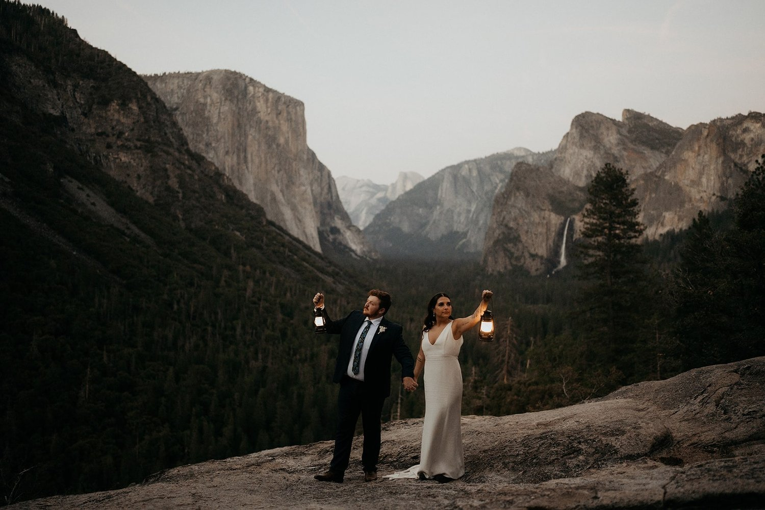 Bride and groom hold lanterns during their Tunnel View elopement in Yosemite National Park.