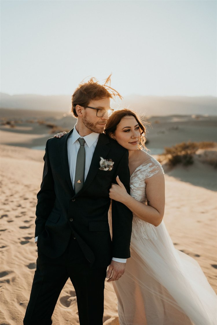 Bride holds on to groom's arm while they take desert elopement photos at Death Valley National Park.