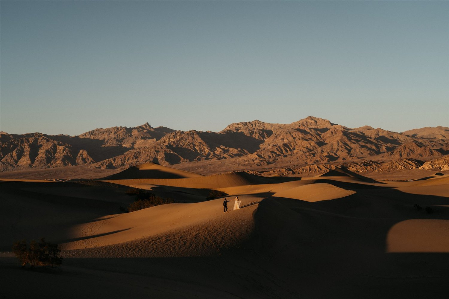 Bride and groom stand in the middle of the sand dunes at Death Valley National Park during sunset.