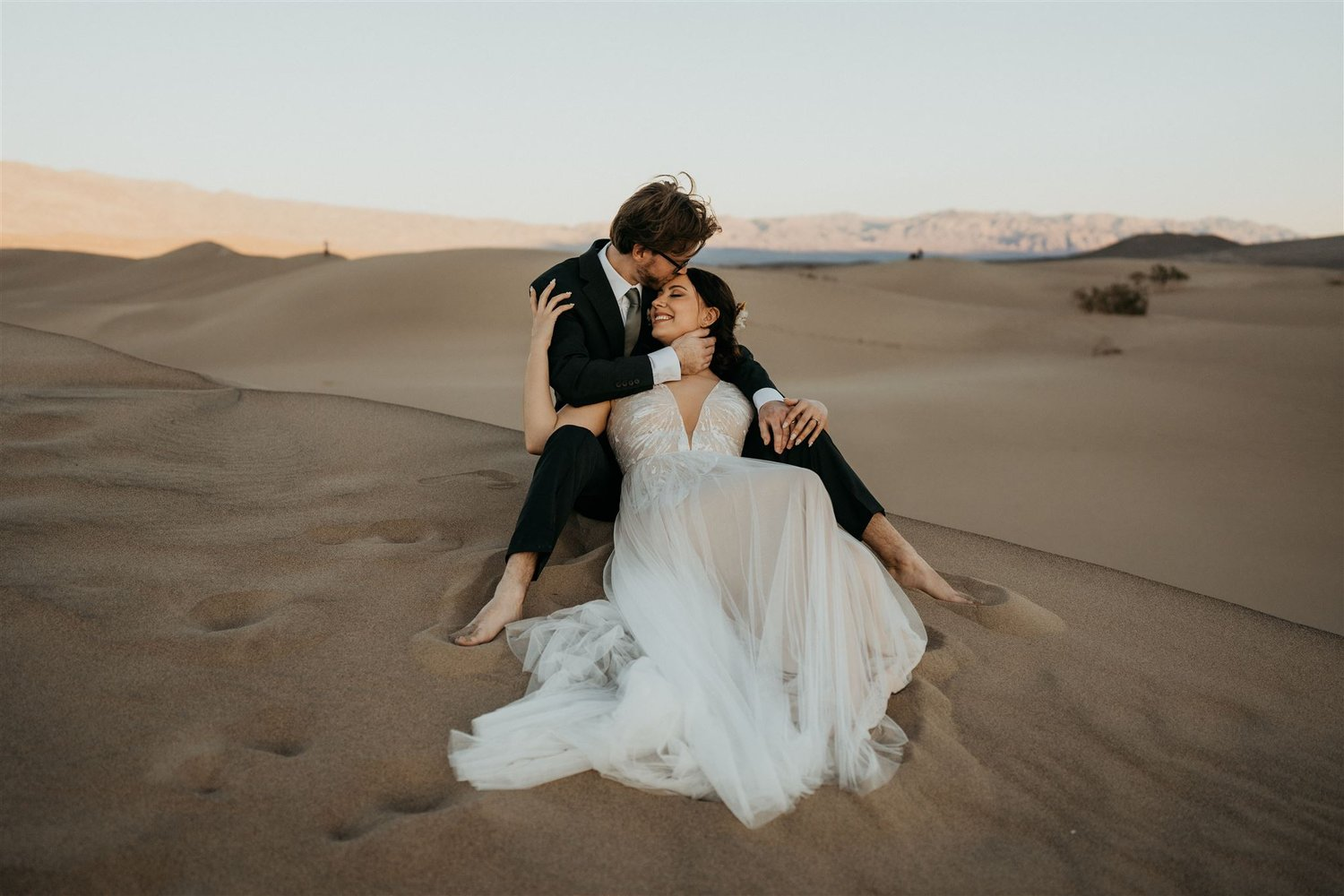Bride and groom sit in the sand dunes during their sunset elopement at Death Valley.