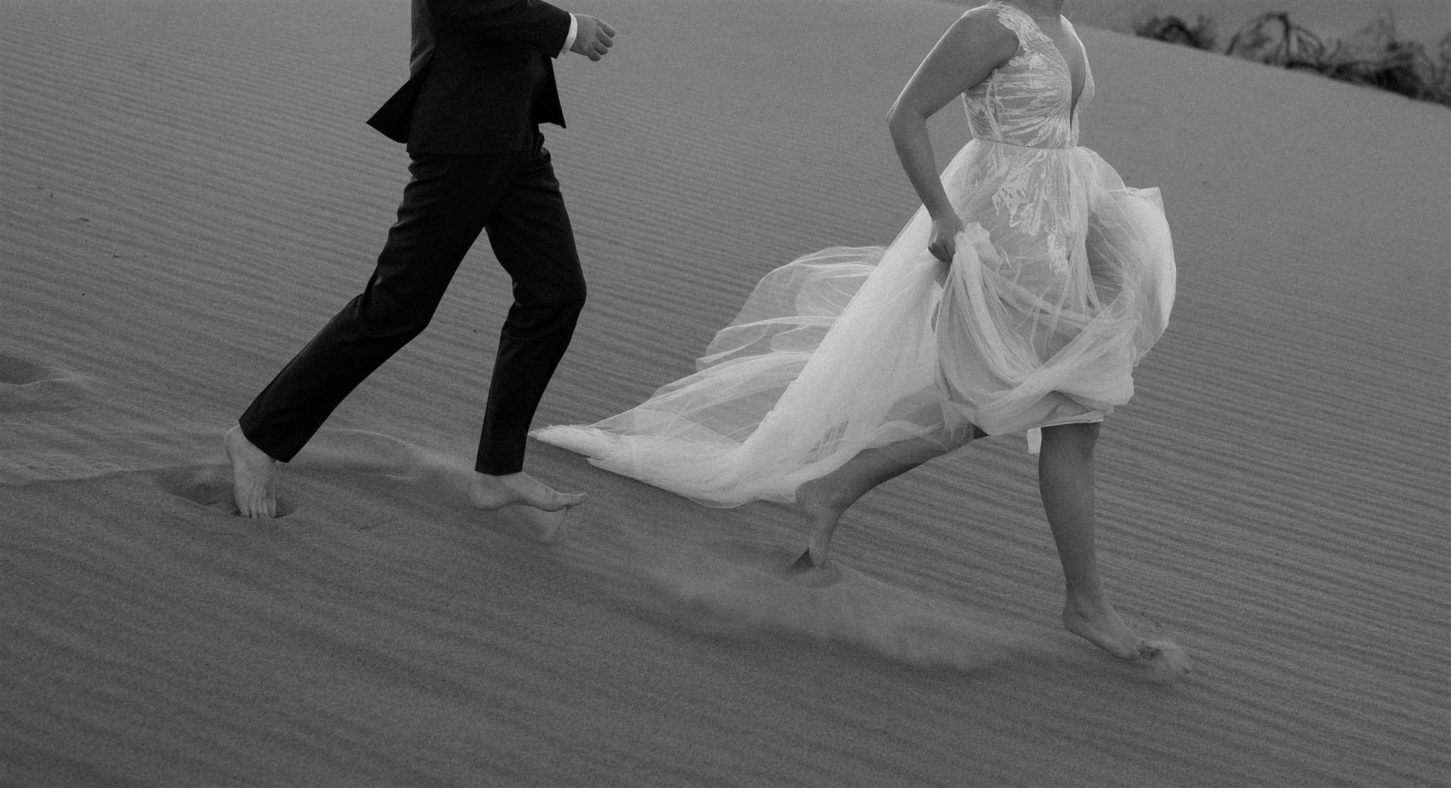 Bride and groom run down the sand dunes during their Death Valley elopement in California.