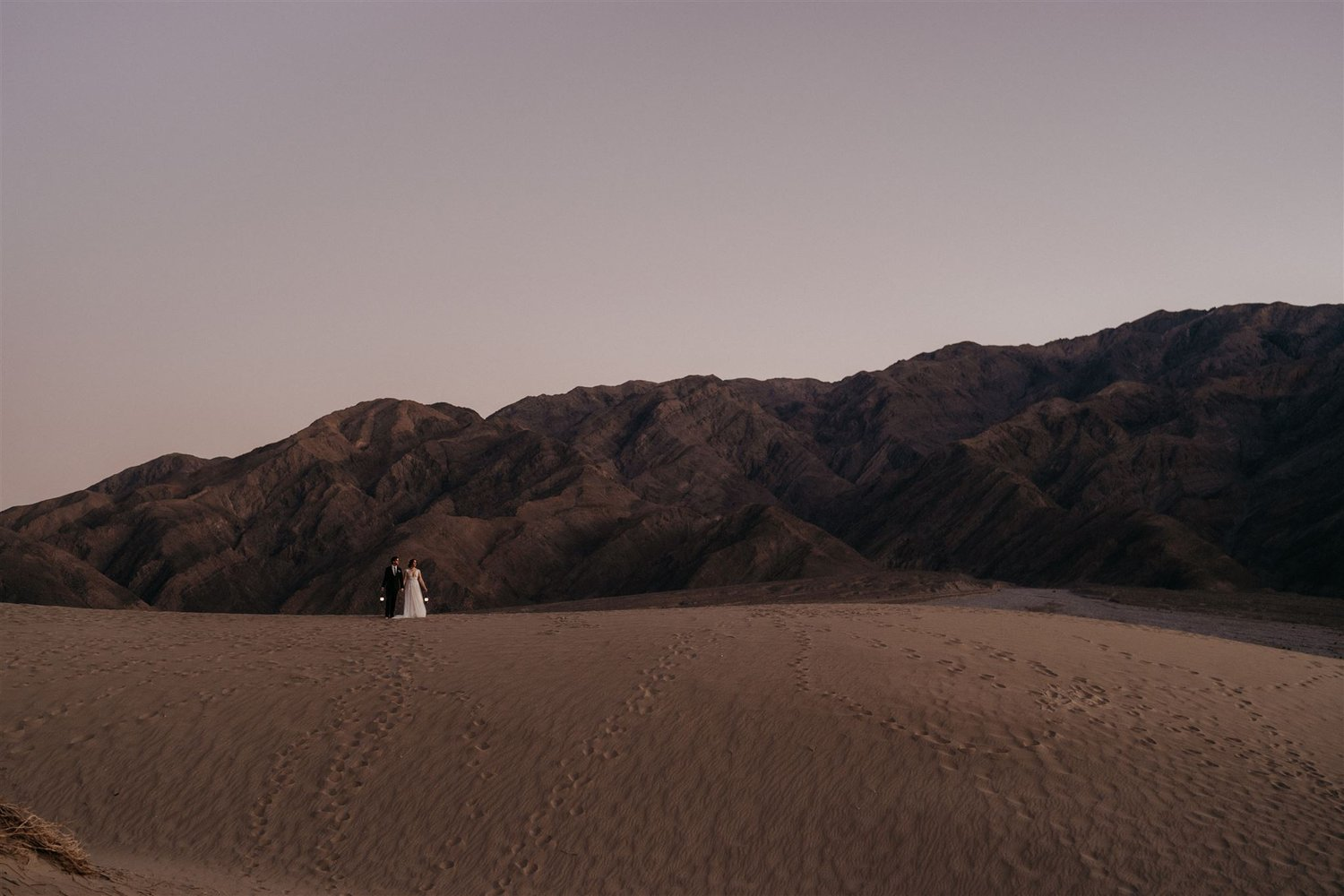 Bride and groom stand on a sand dune ledge during their California elopement at Death Valley.
