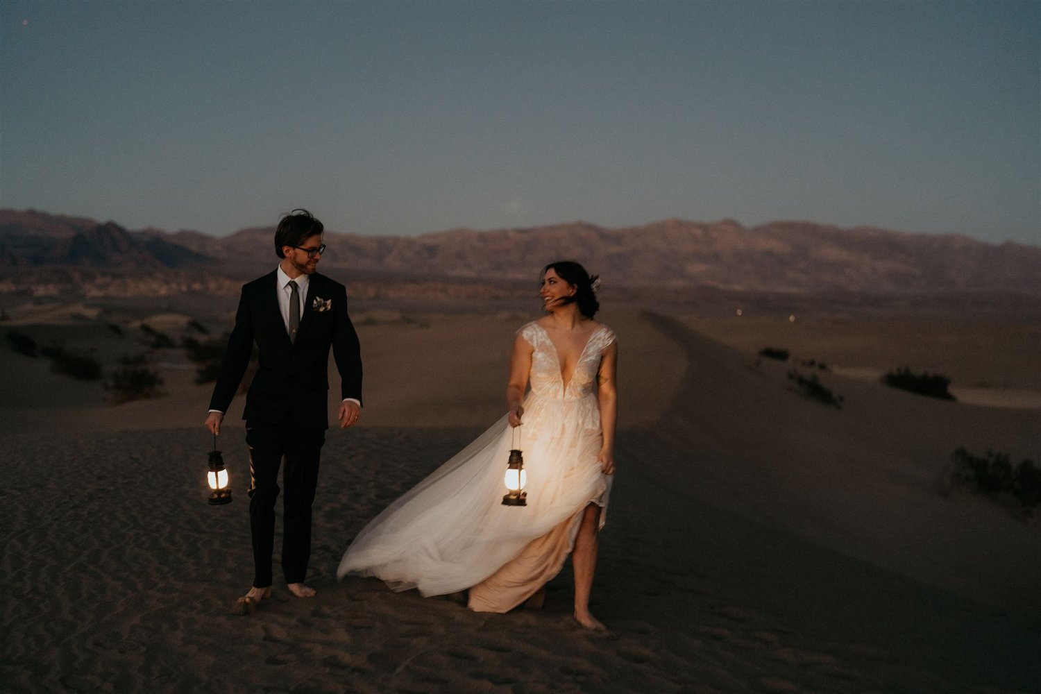 Bride and groom hold lanterns during blue hour at their Death Valley elopement in California.
