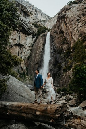 Bride and groom stand on a fallen log during their Yosemite elopement photos at Yosemite Falls.