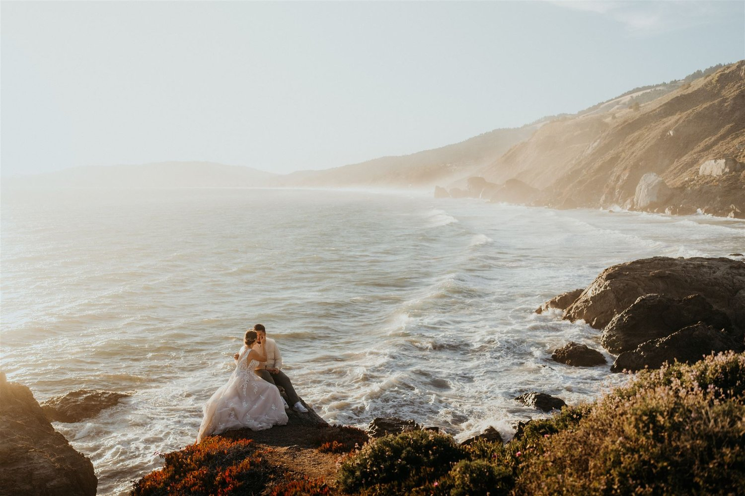 Bride and groom sit on the cliffs overlooking the ocean during their elopement in Marin Headlands, California.