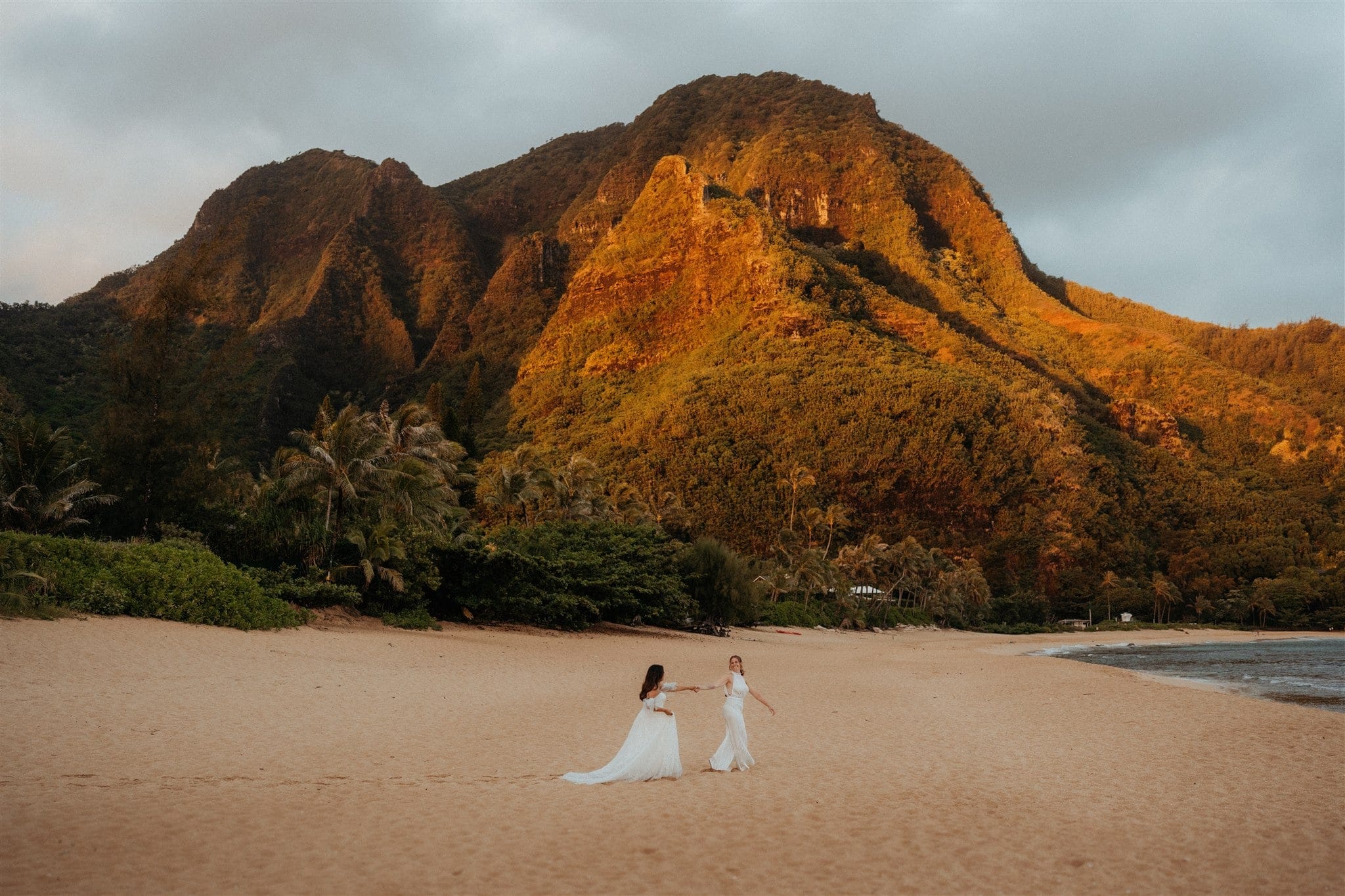 Two brides run across the beach during their elopement adventure photos