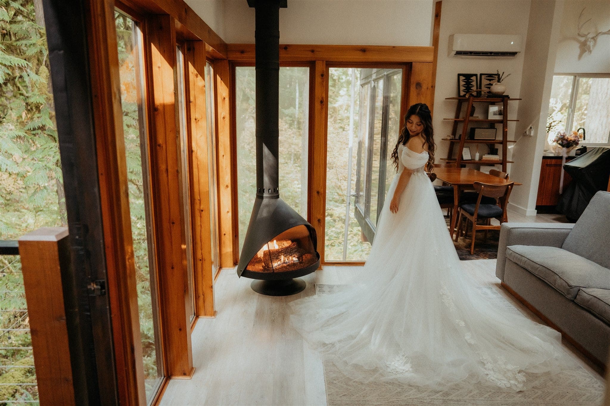 Bride stands next to a wood stove in her white wedding dress