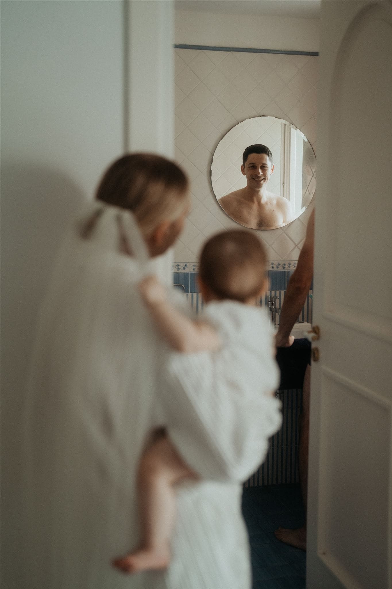 Bride holds baby while groom gets ready for their vow renewal
