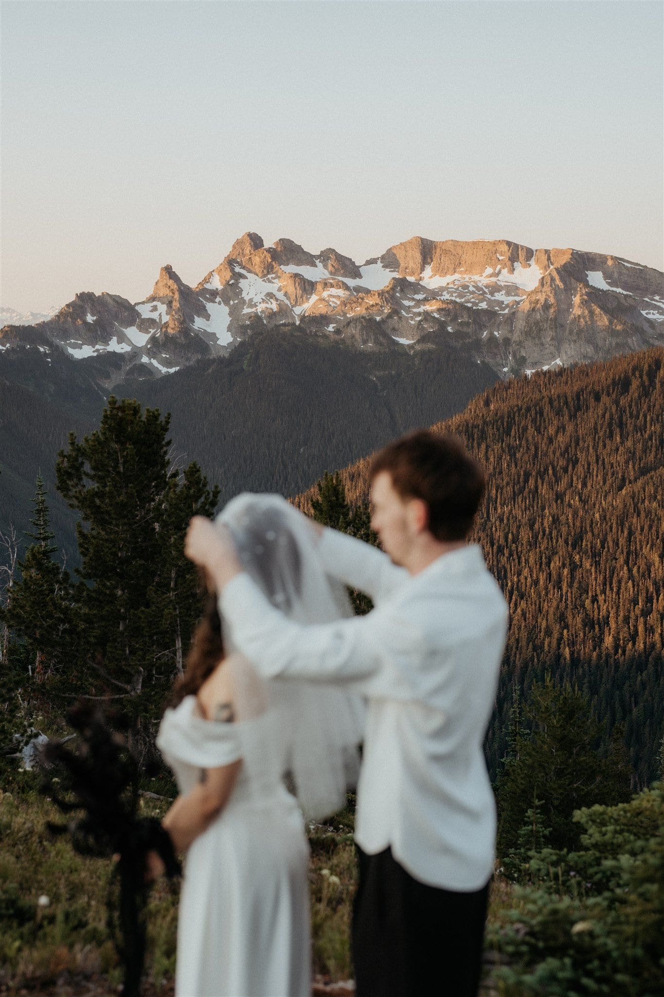 Groom helps bride place veil on her head during their elopement