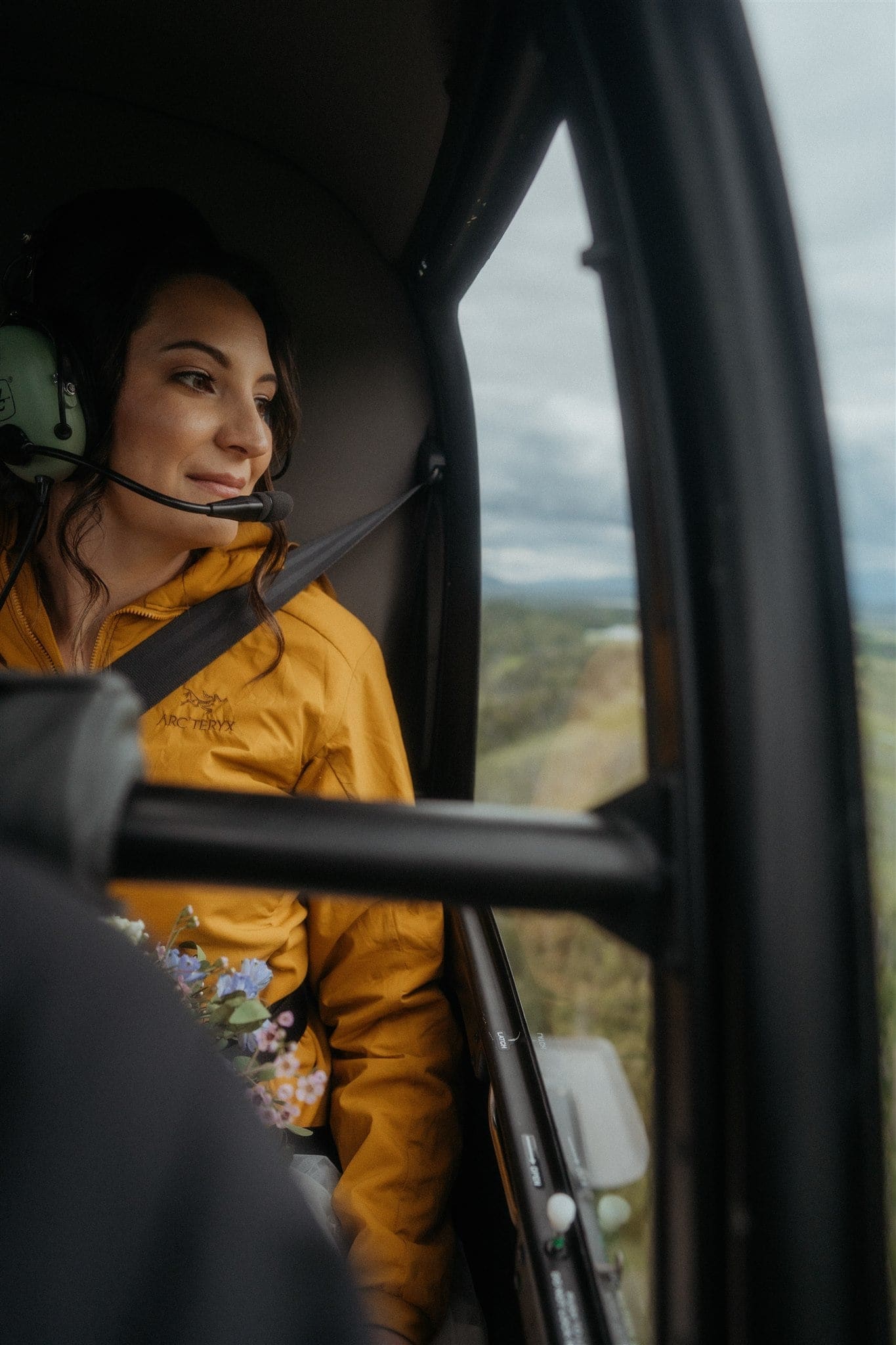 Bride looks out the window while riding in a helicopter over Alaska
