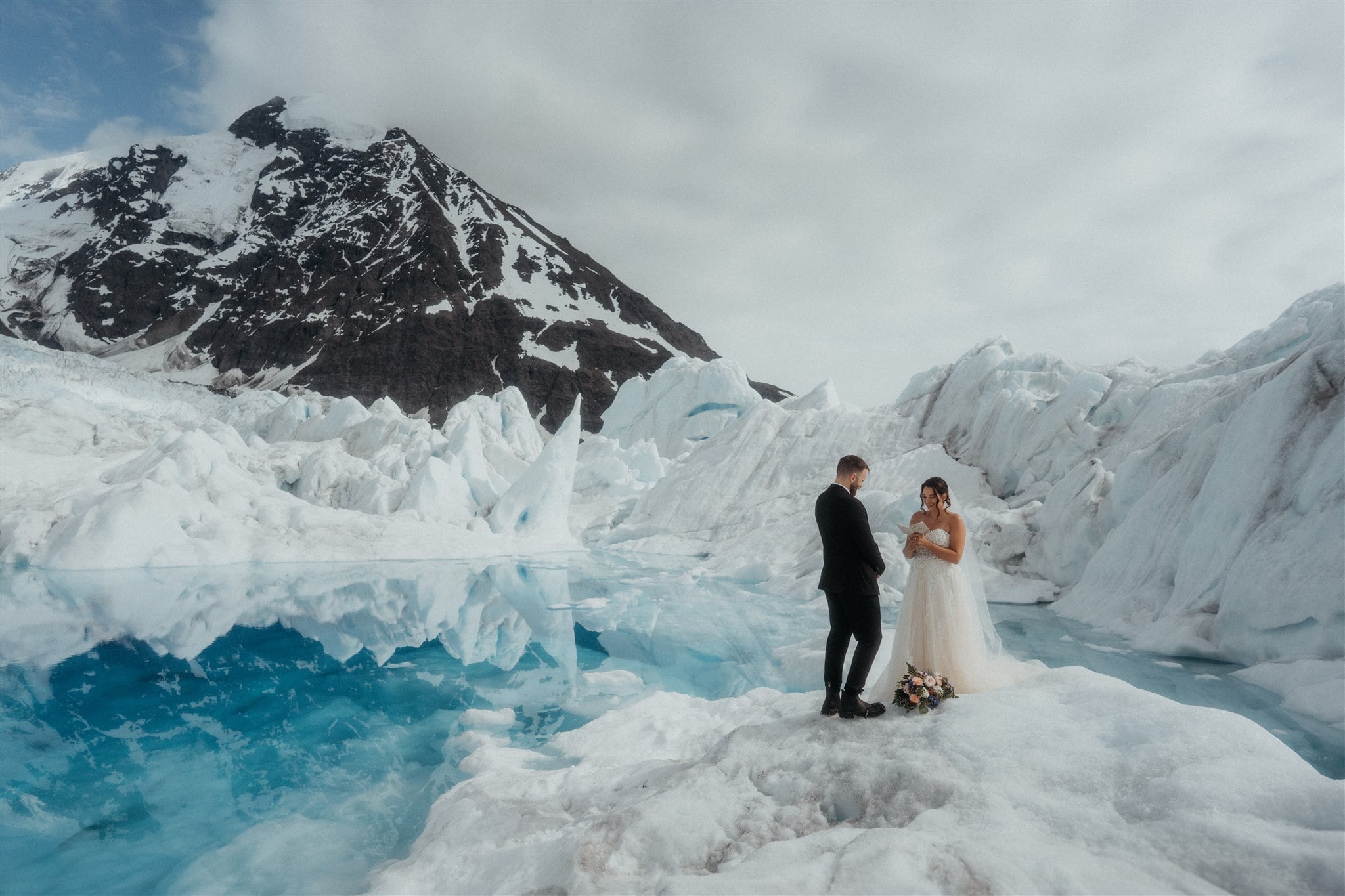 Bride and groom exchange vows on an icy glacier during their elopement