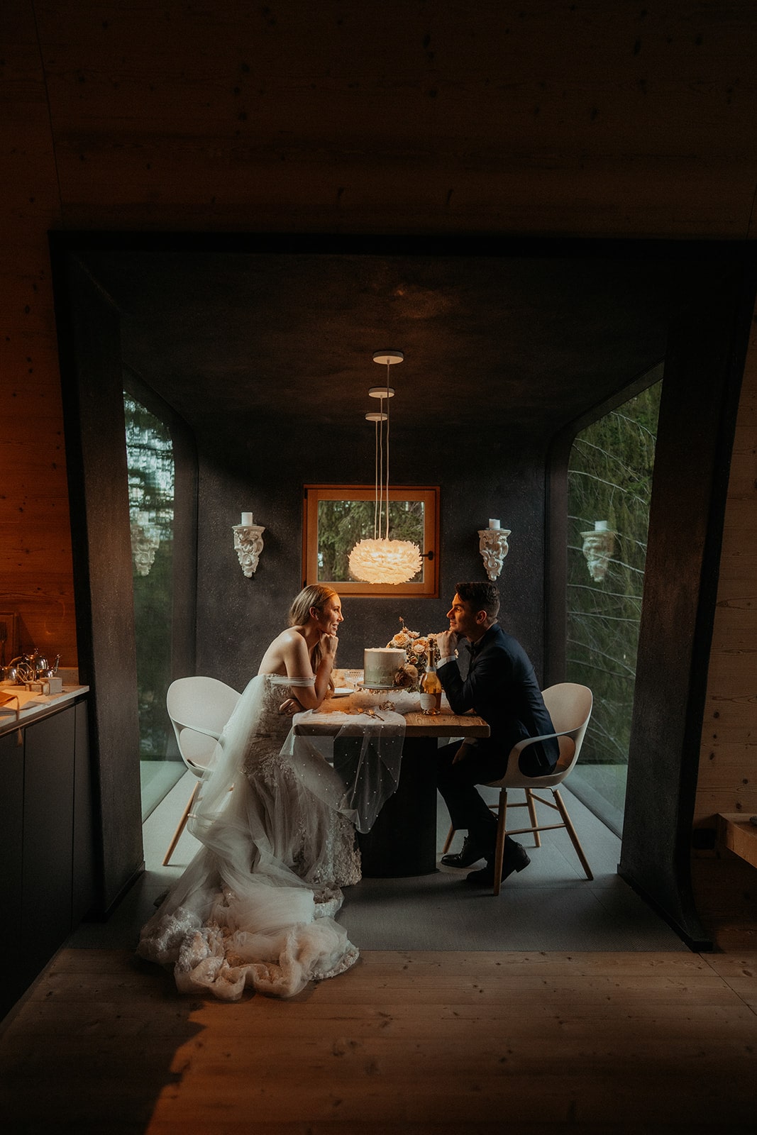 Bride and groom sit at a table in their Airbnb for their cake reception