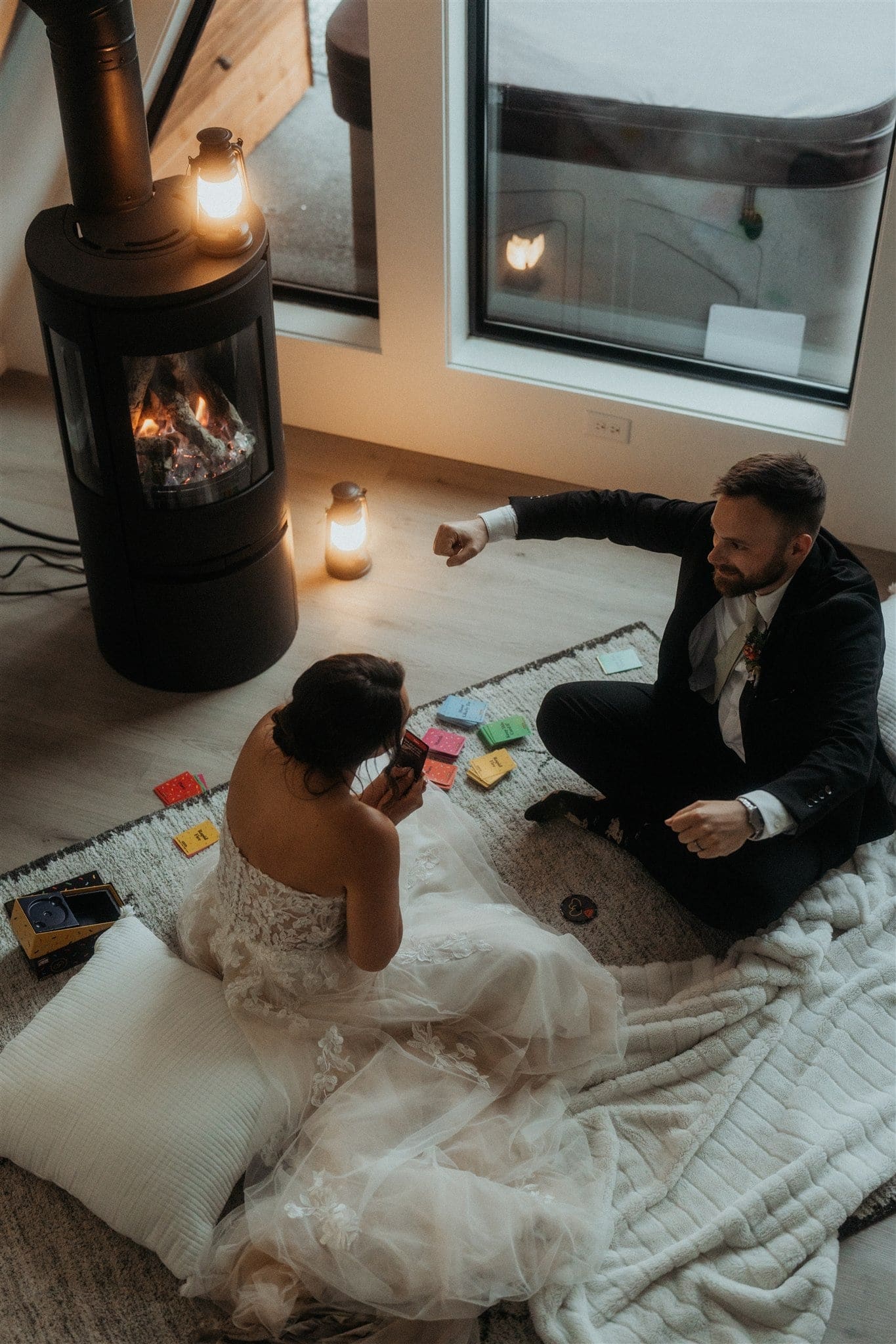 Bride and groom sit on the floor of their Airbnb and play board games