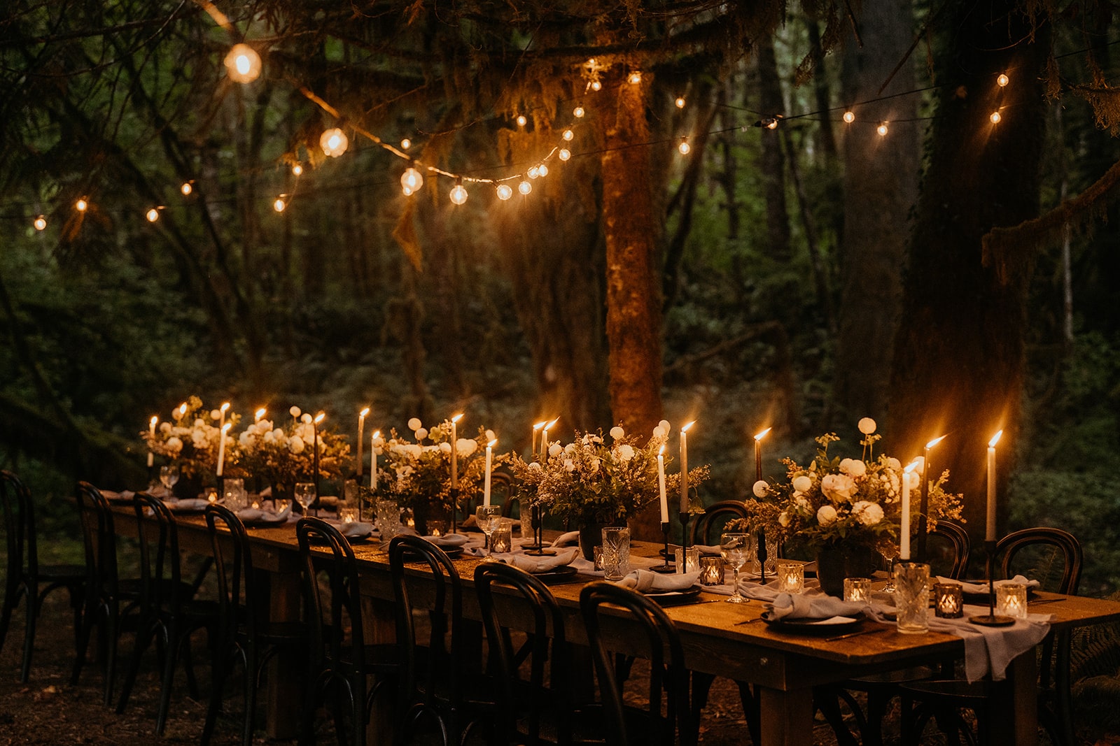 Moody candlelit forest wedding reception under string lights at Mt Baker Haus Lodge