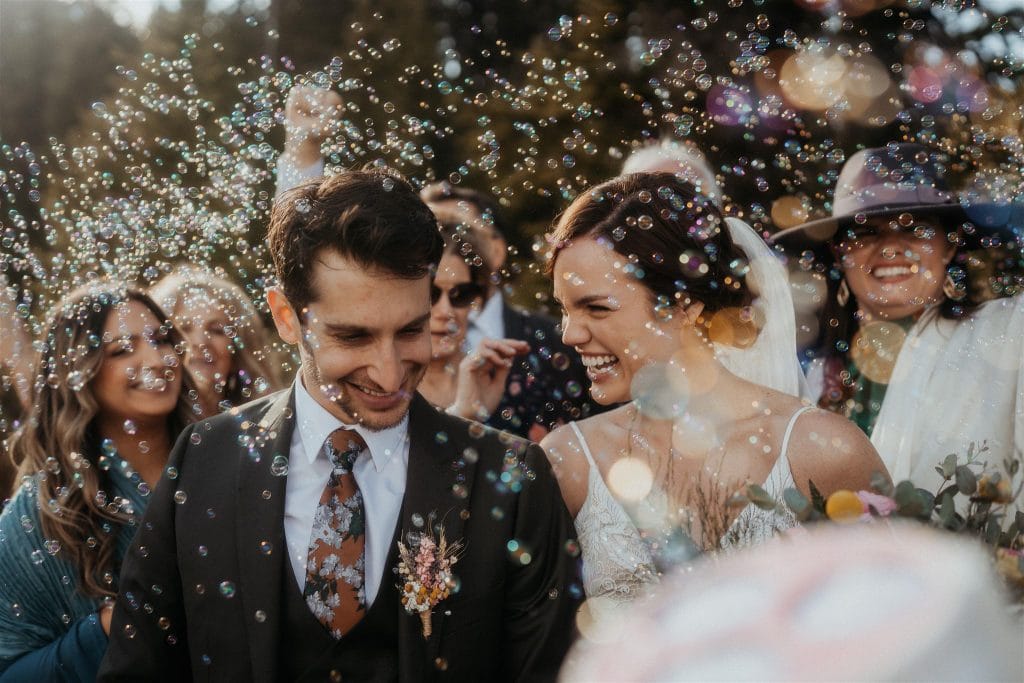 the bride and groom getting bubbles blown on them.