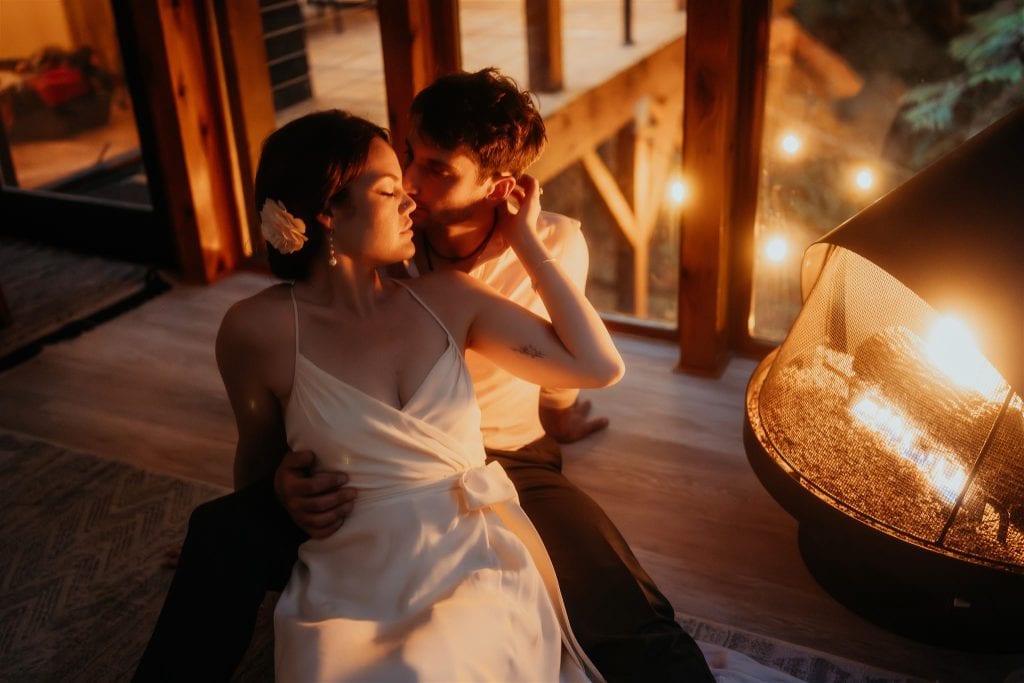 the newlyweds kissing in front of a fireplace.