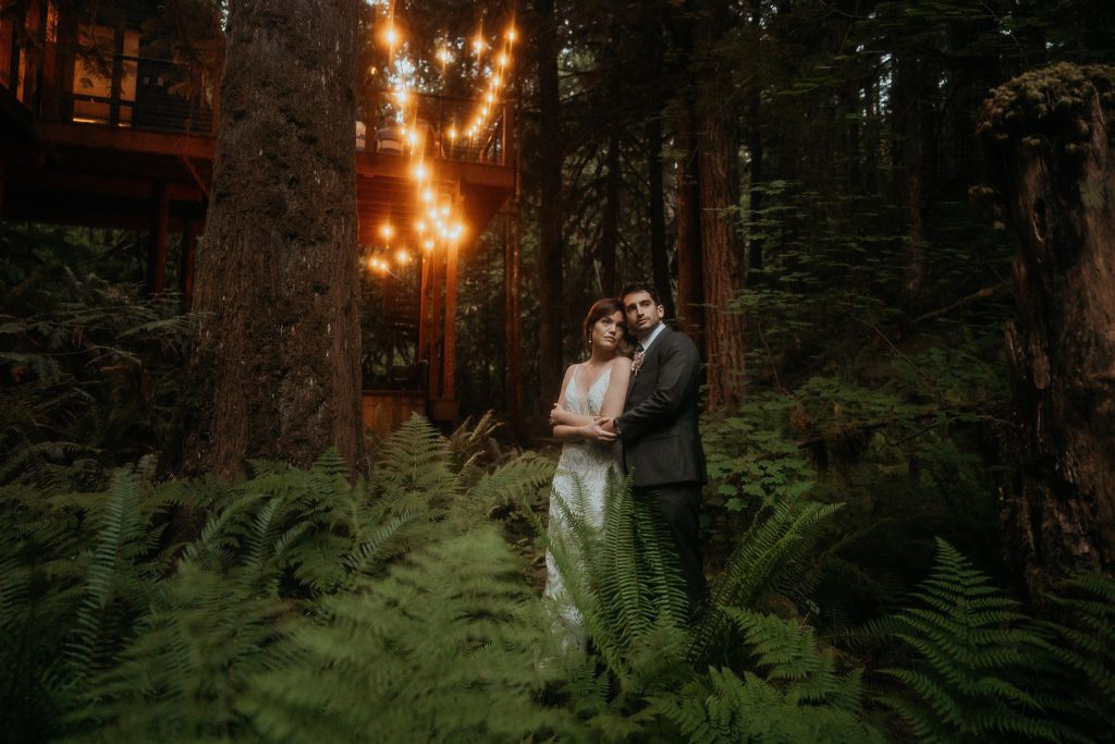 the newlyweds holding each other under twinkling lights in the forest during their Washington micro wedding.