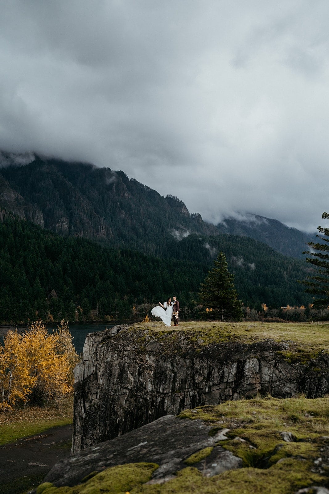 Bride and groom stand on a cliff overlooking the Columbia River Gorge.
