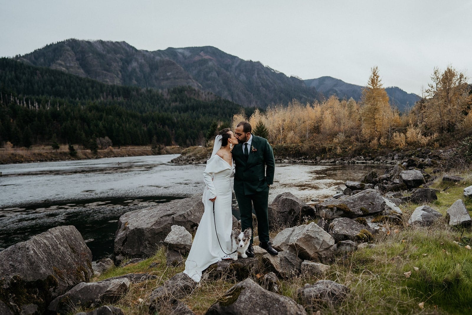 Bride and groom kiss while holding their dog's leash at their Columbia River Gorge elopement.