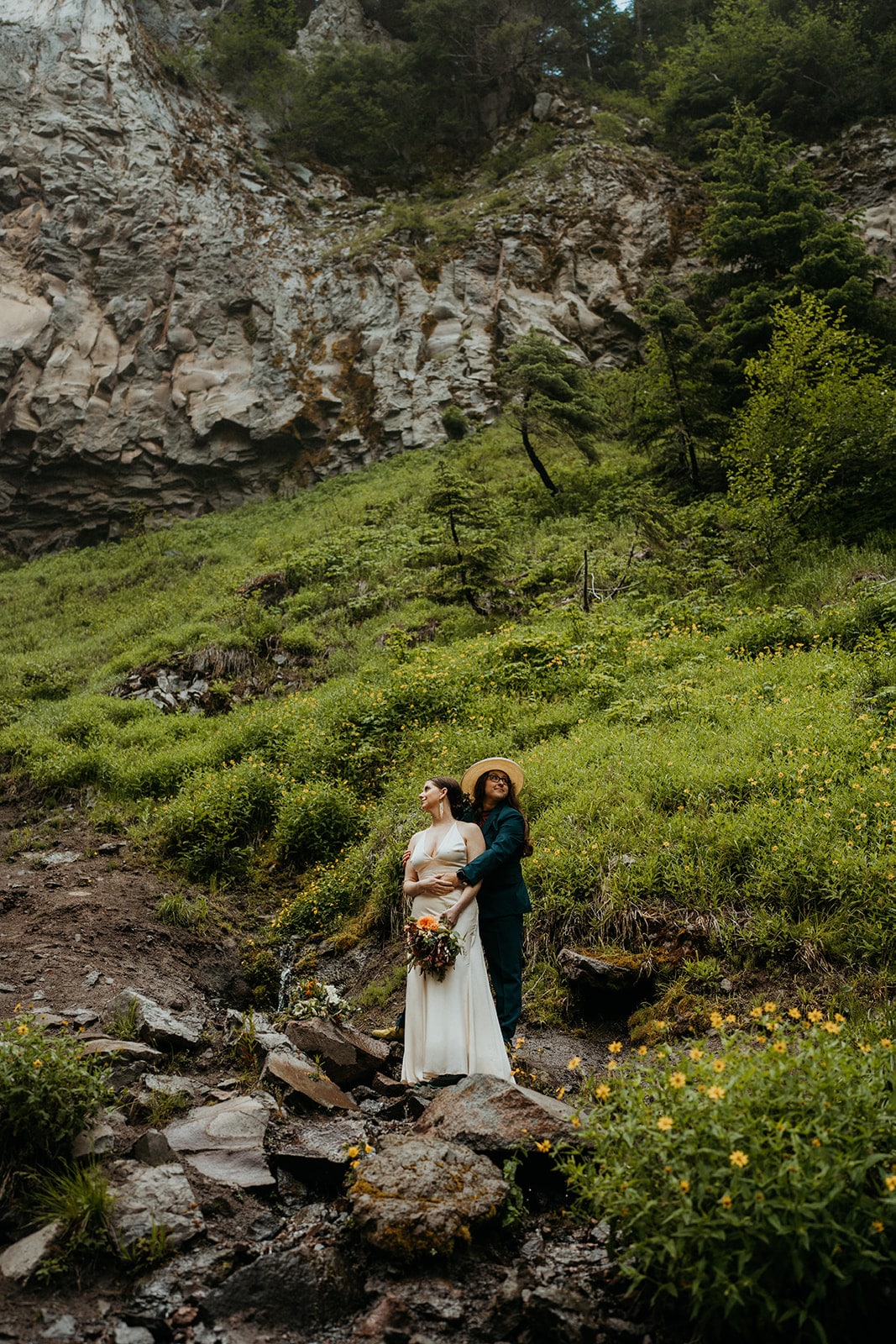 Brides hug while standing on a grassy hill during their elopement in the Columbia River Gorge.