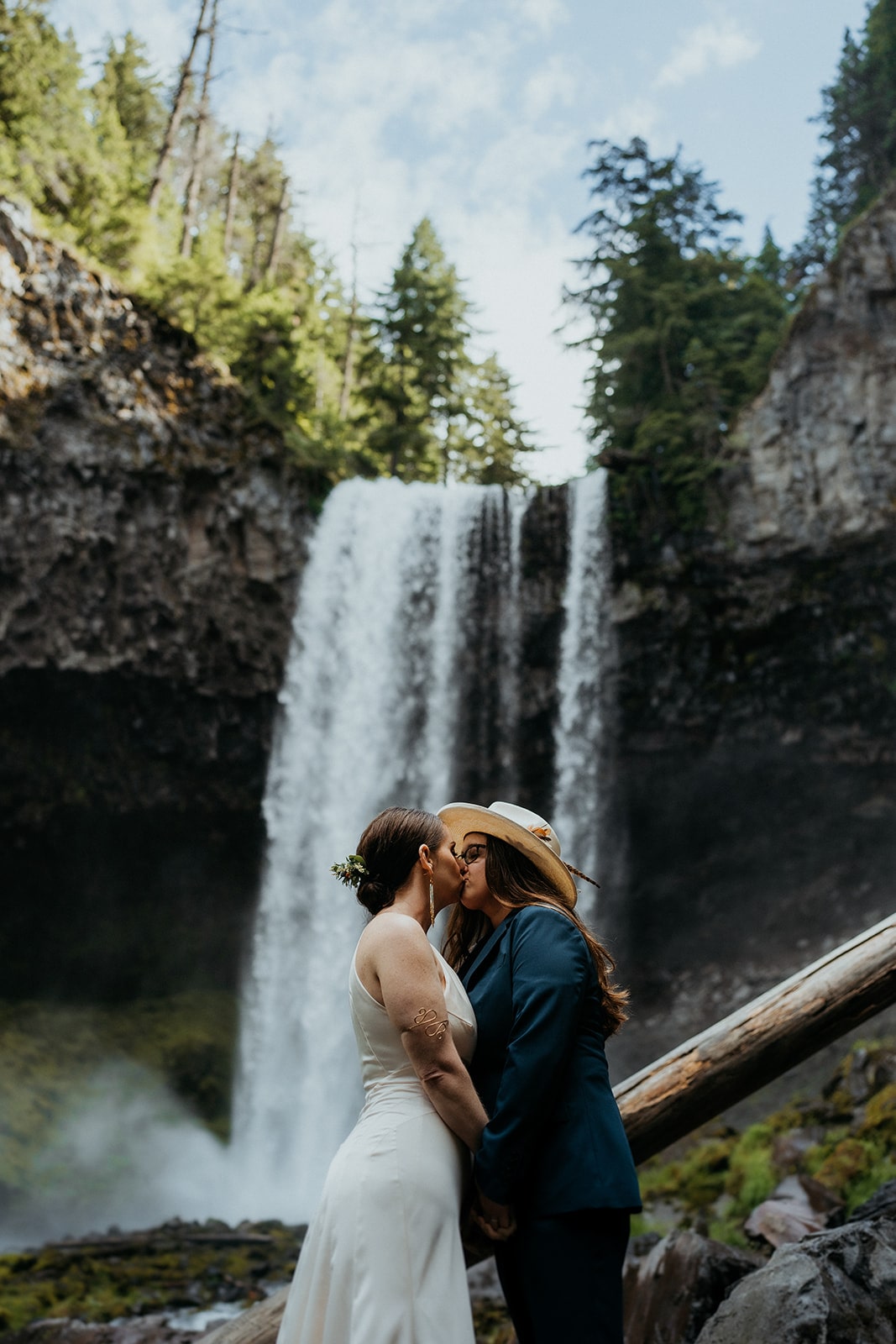 Two brides kiss in front of an Oregon waterfall in the Columbia River Gorge.