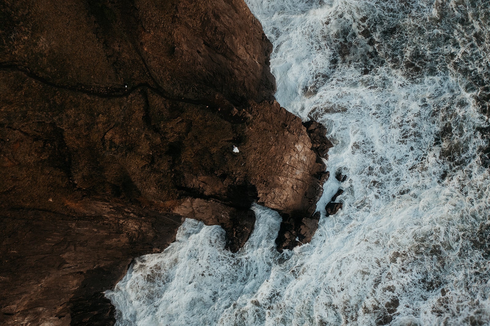 Two brides sitting on the cliff watching the waves for their Oregon Coast elopement.
