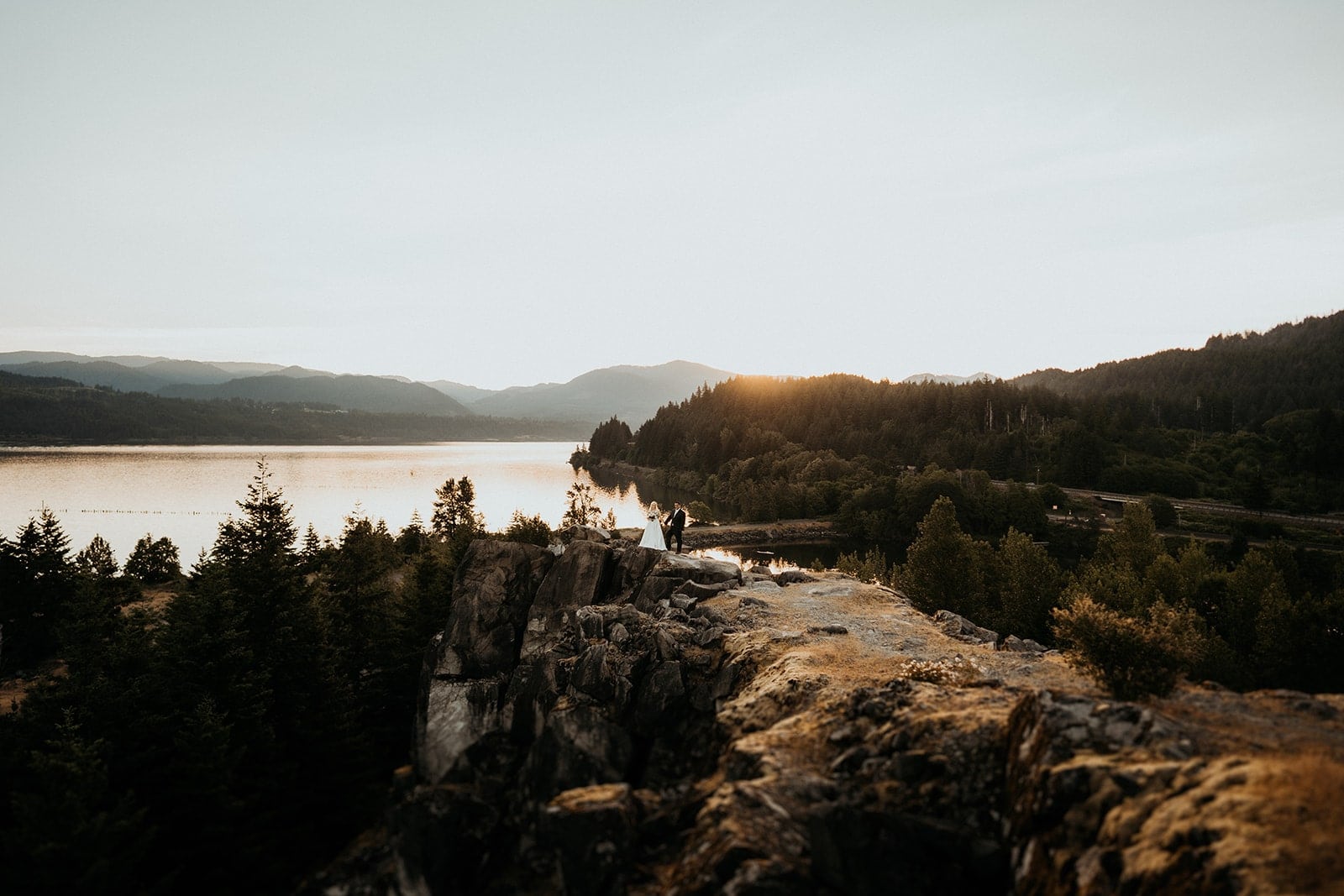 Bride and groom stand on a cliff ledge during their Columbia River Gorge elopement in Oregon.