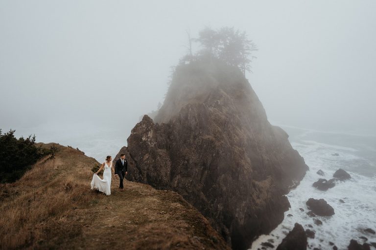 Bride and groom holding hands walking along the cliffs on the Southern Oregon Coast.