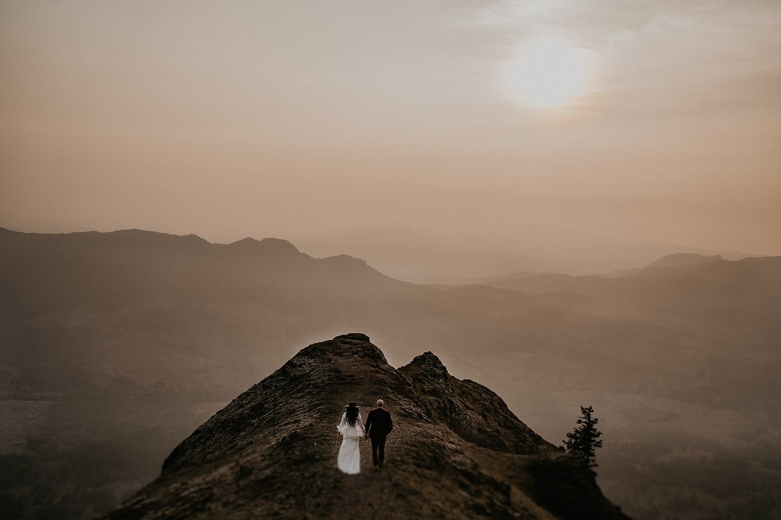 Bride and groom walk up a mountain trail at sunset during their Bend, Oregon elopement.