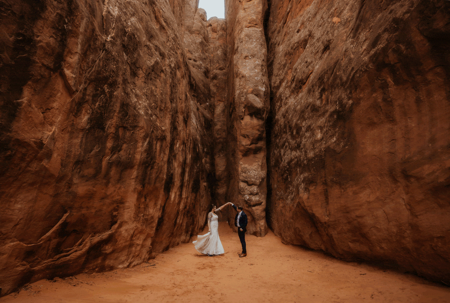 a couple dancing in a slot canyon while they elope in moab. 