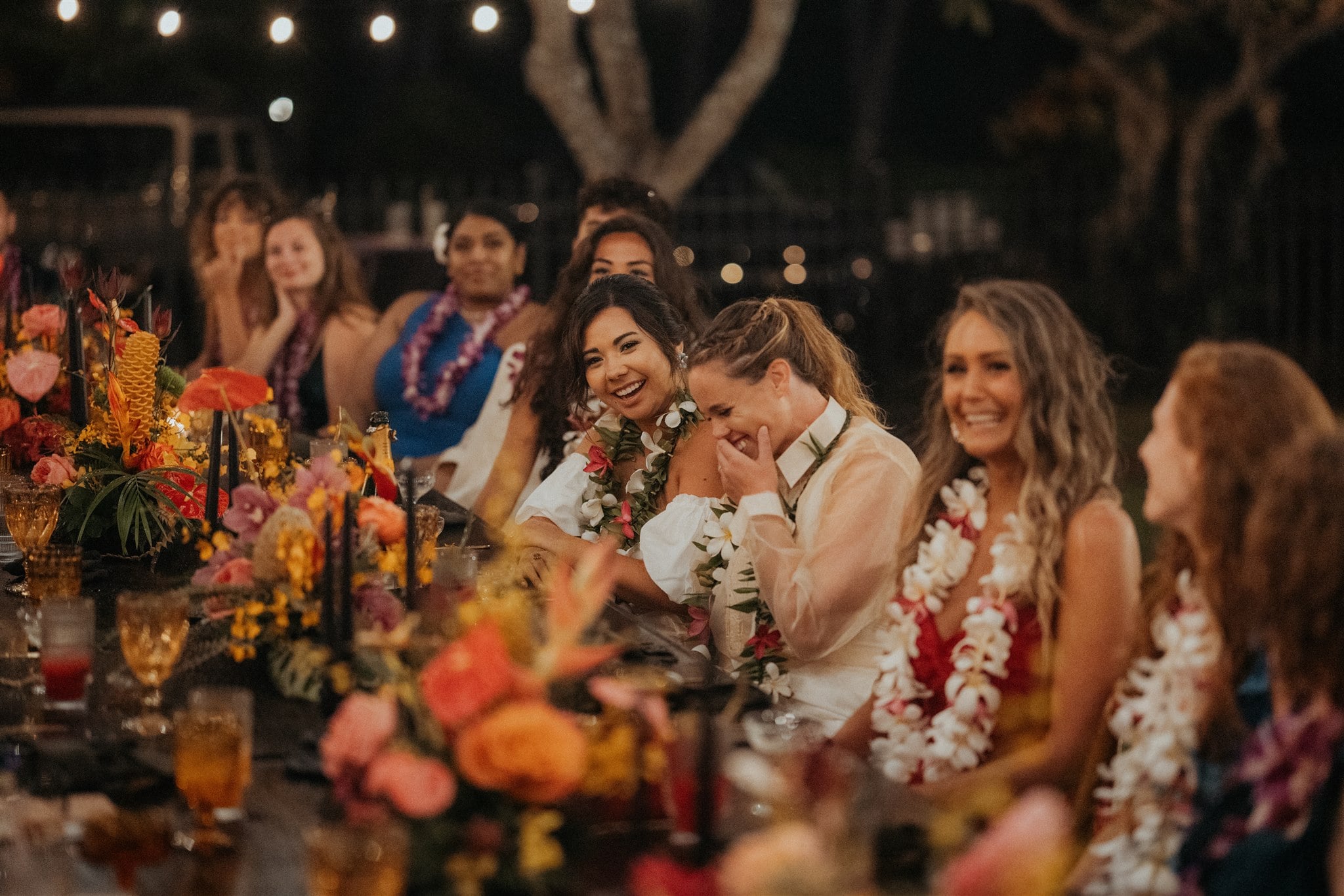 Brides laugh as guests give speeches during their Kauai micro wedding reception dinner.