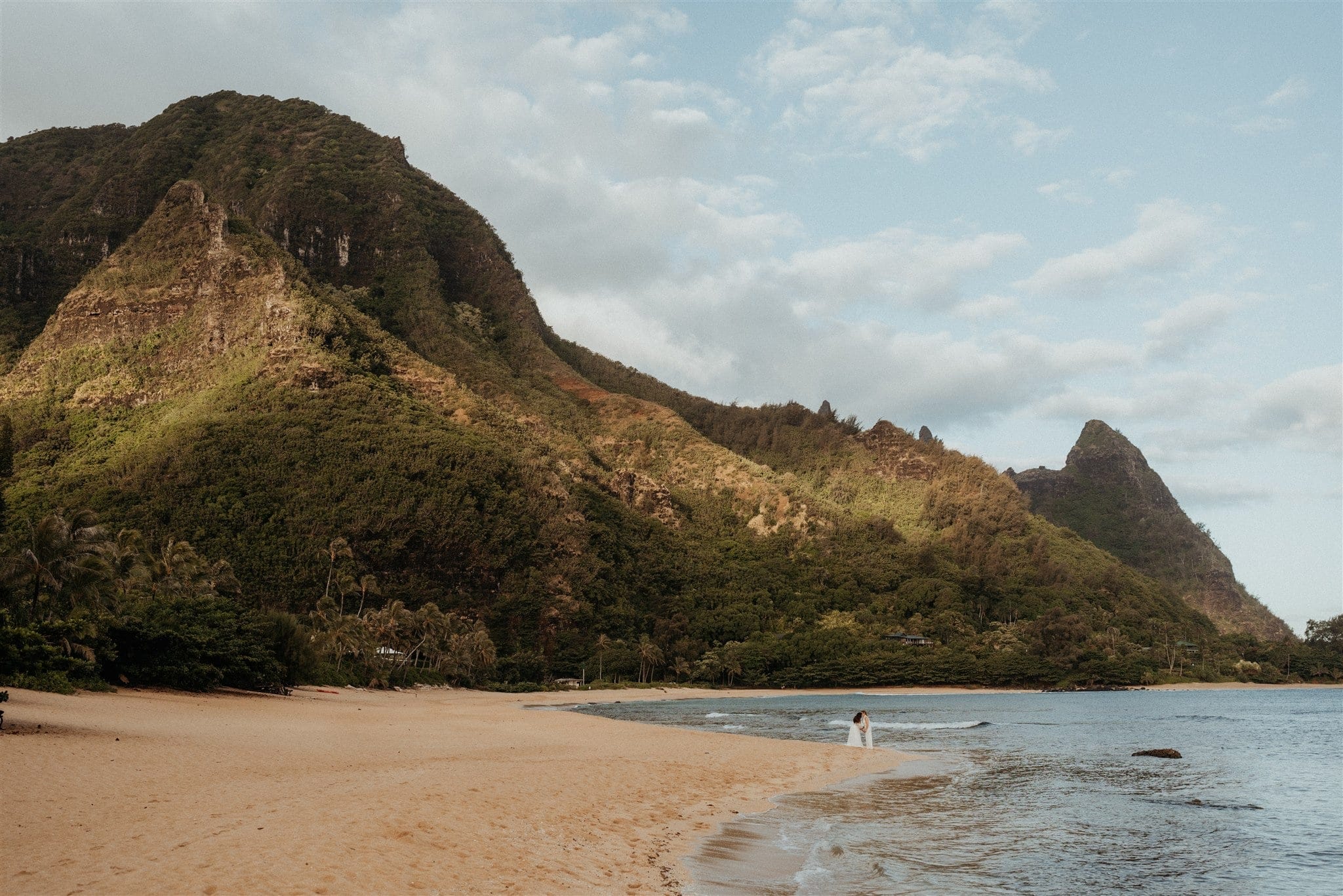Brides walk out an inlet at Tunnels Beach in Kauai.