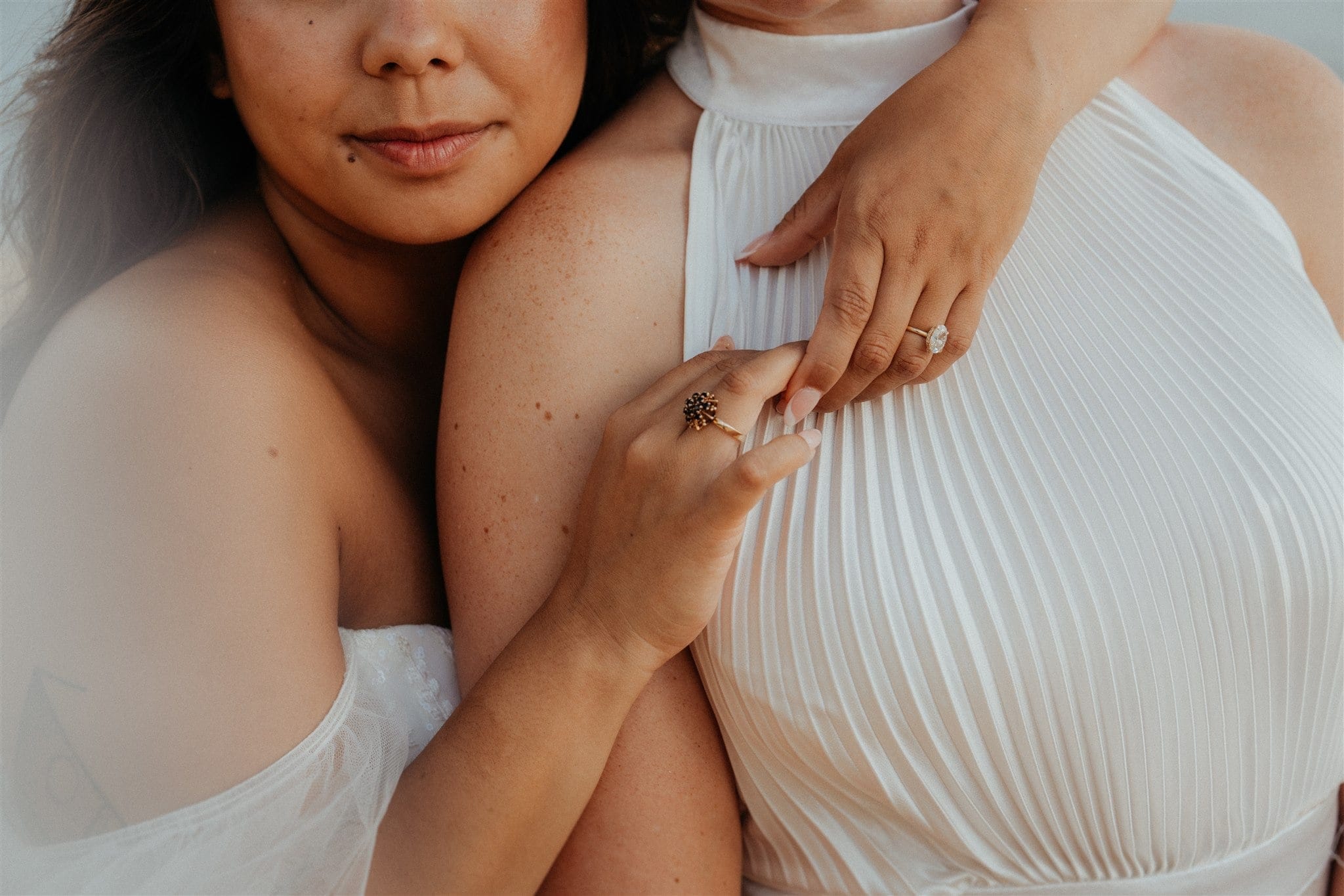 Bride wraps her arms around other bride's neck during their micro wedding photos at Tunnels Beach.
