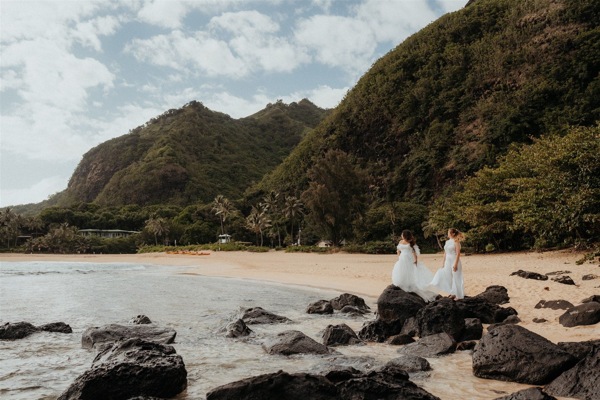 Brides walk out along the rocks at Tunnels Beach during their Kauai micro wedding.