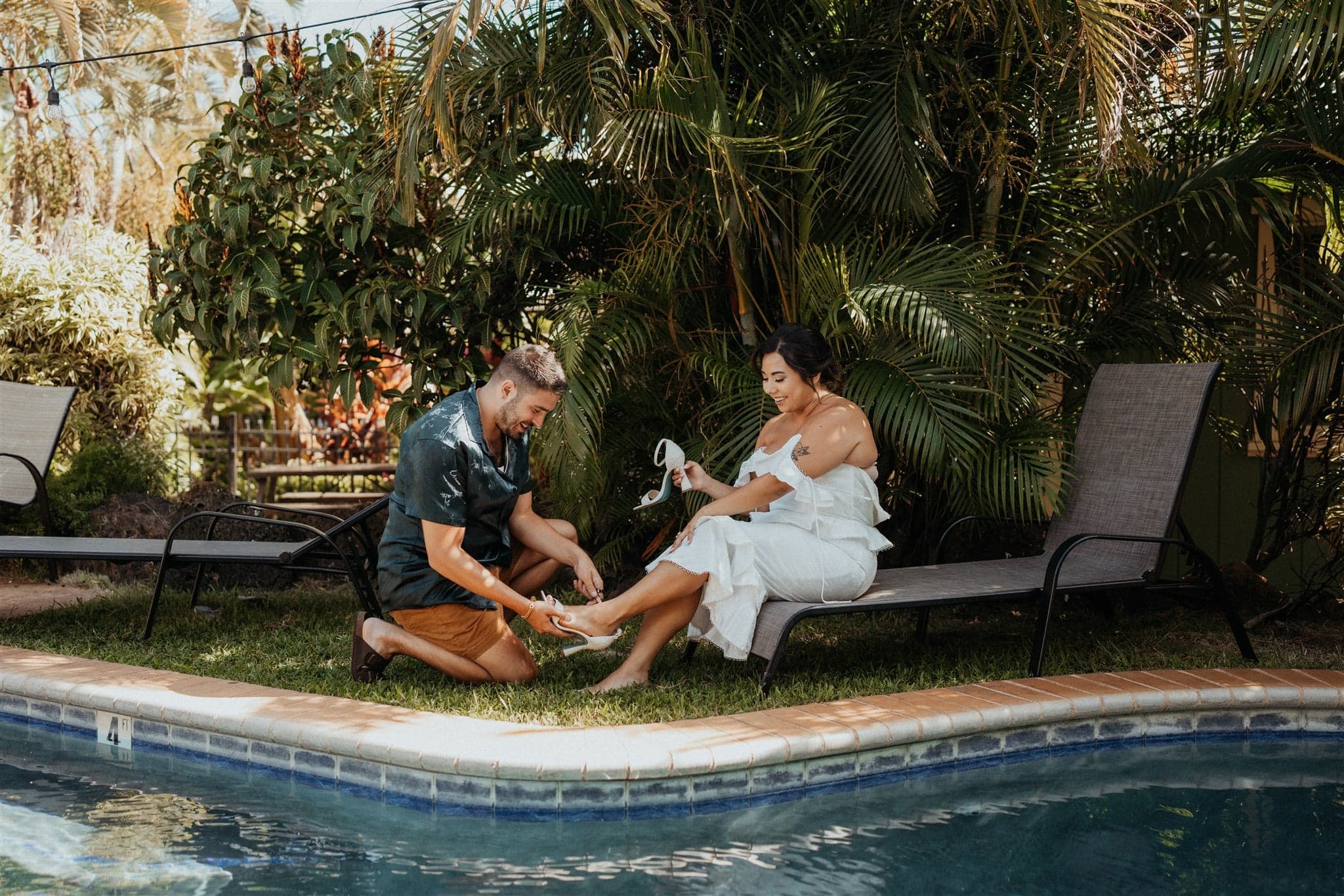 Friend helps bride put on her sandals for her micro wedding in Kauai.