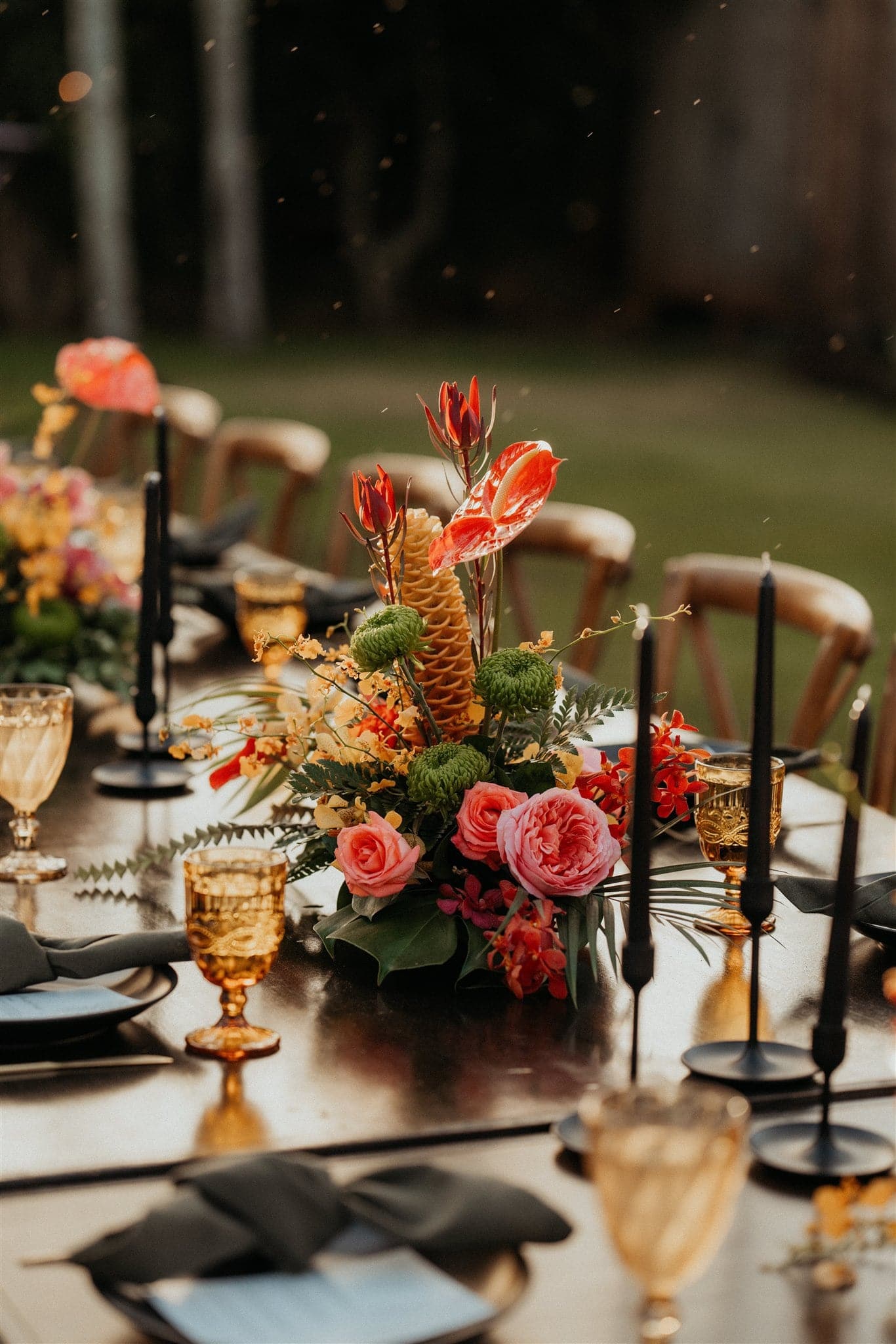 Bright pink and orange tropical florals line a Kauai micro wedding dinner reception table in the backyard of an Airbnb.
