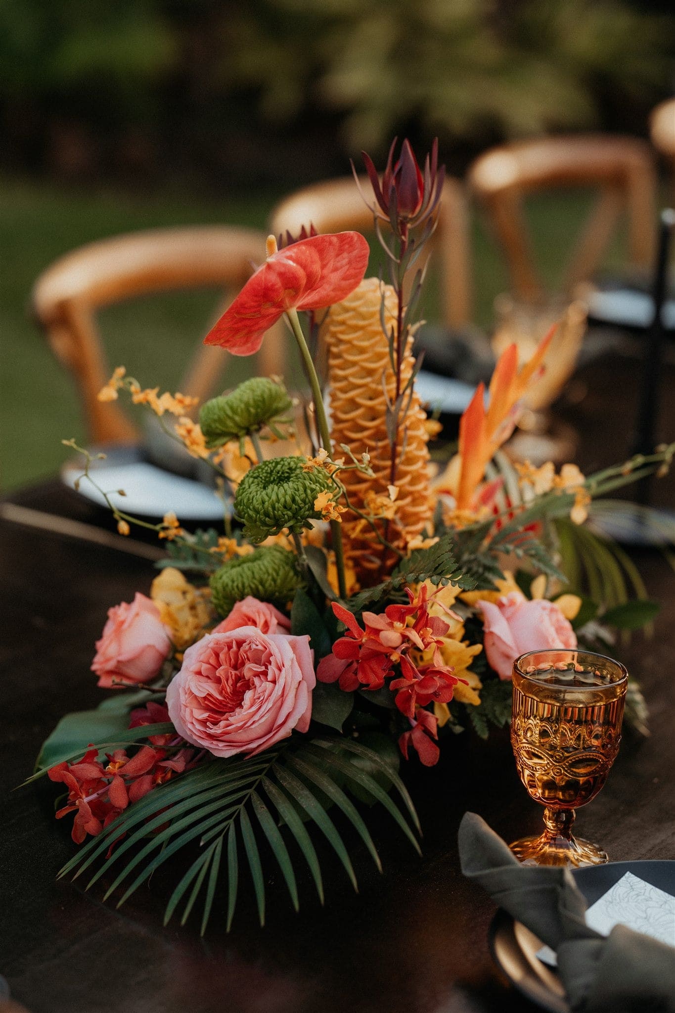 Bright pink and orange tropical florals line a Kauai micro wedding dinner reception table in the backyard of an Airbnb.