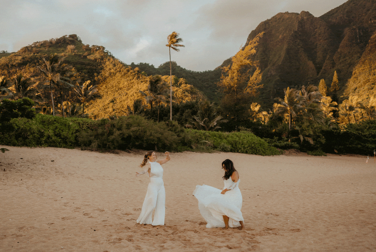 Brides dance around on Tunnels Beach in Kauai at sunrise.