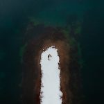 Bride and groom lay on a snowy peninsula surrounded by water during their Washington winter elopement.