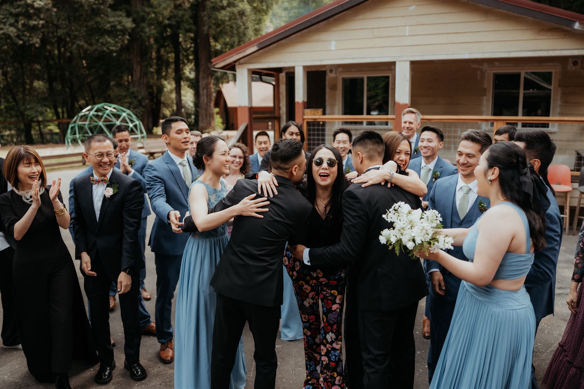 Guests hug grooms before their wedding weekend ceremony in California.