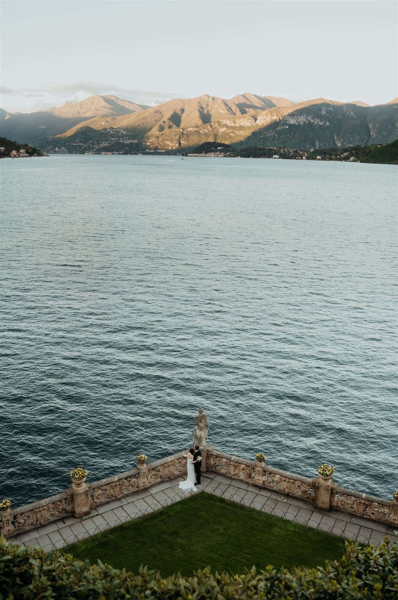 Bride and groom stand on a veranda overlooking Lake Como during their multi-day elopement in Italy.