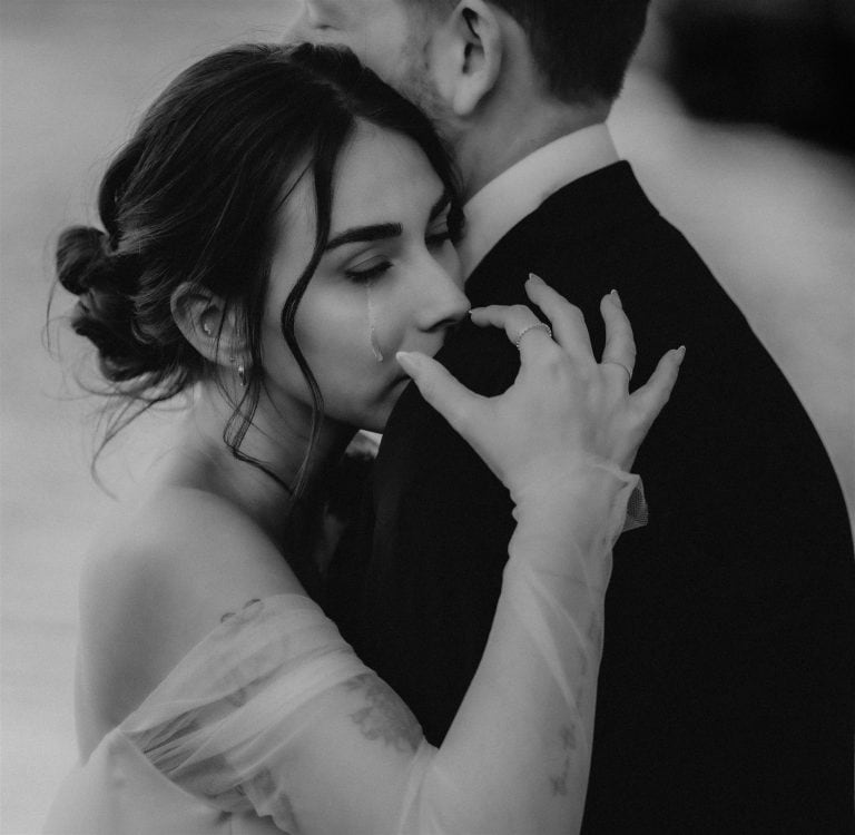 A tear rolls down bride's cheek as she hugs groom during their multi day wedding in Italy.