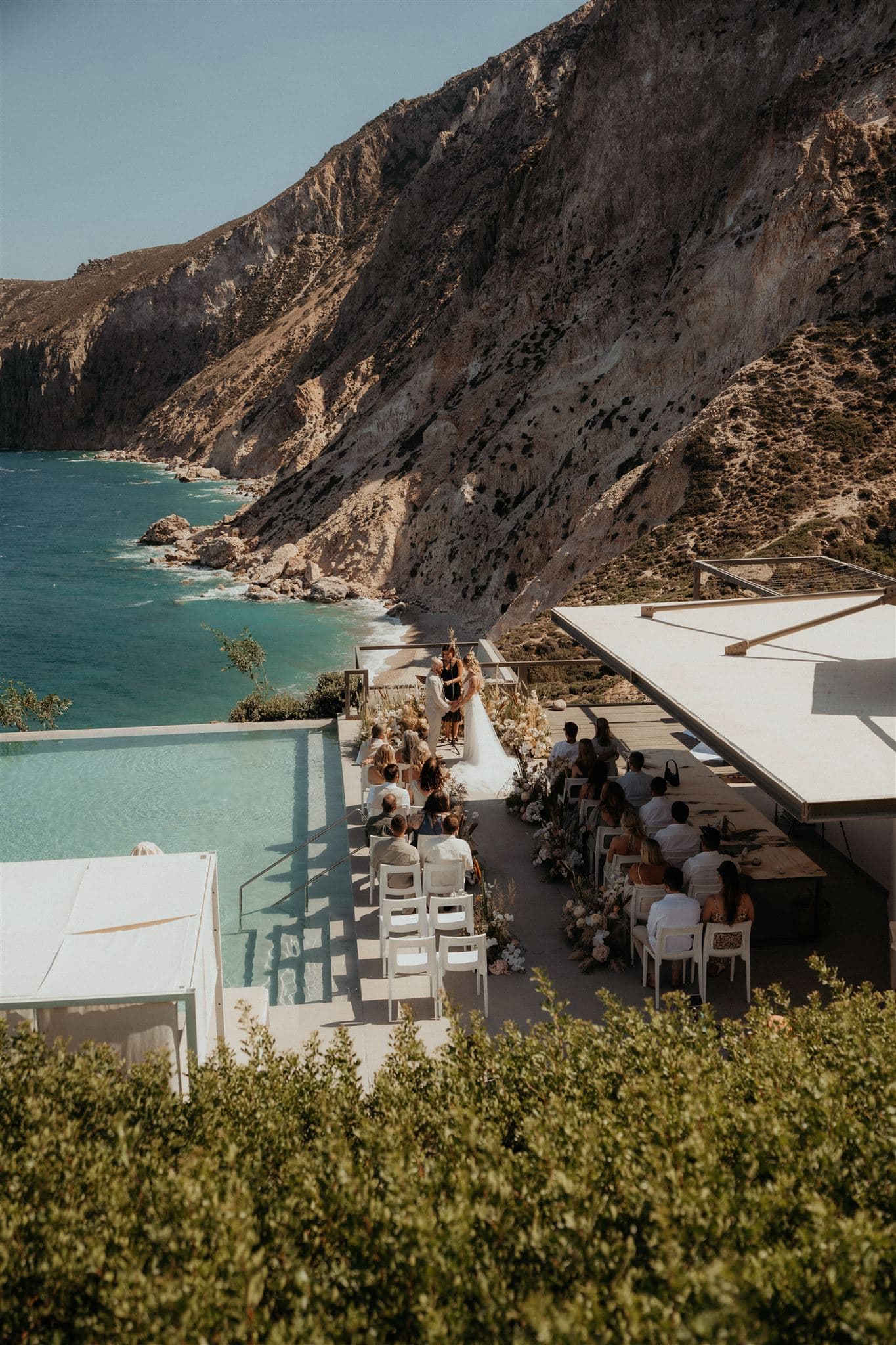 Guests sit at an outdoor ceremony during a wedding weekend in Greece.