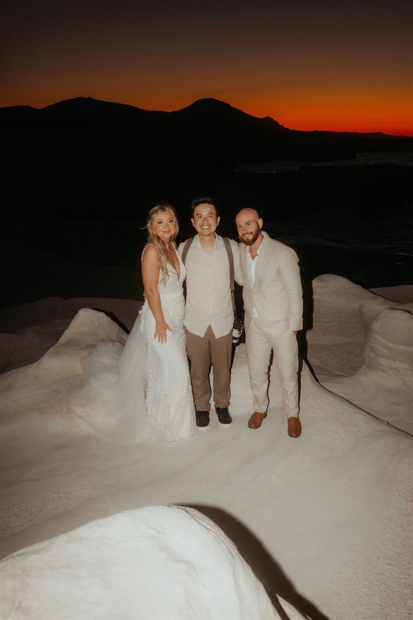Bride and groom take a photo with their Greece destination wedding photogrpaher at Sarakiniko Beach.