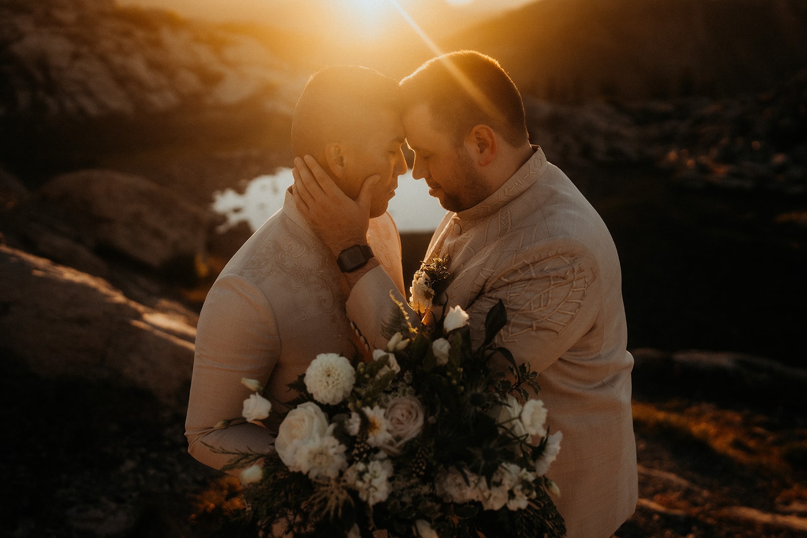 Grooms touch foreheads during their fire lookout elopement at sunrise.