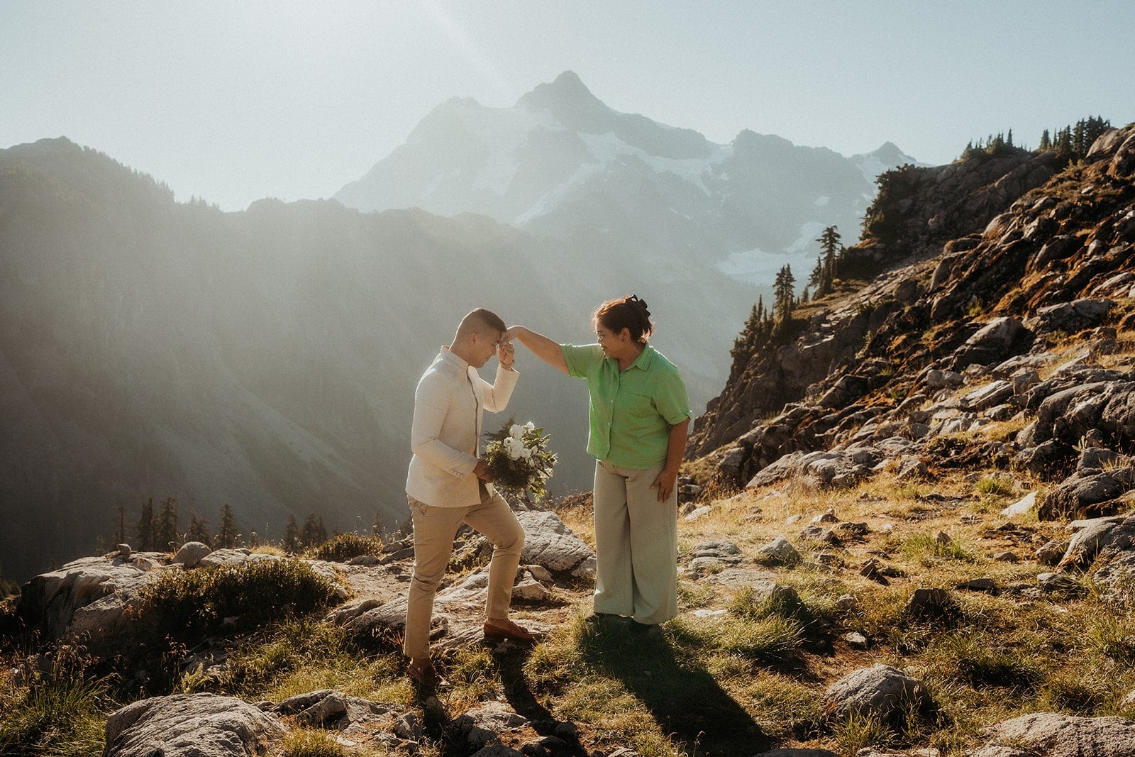 Groom lifts his aunt's hand for a mano po ritual at his elopement in the mountains.