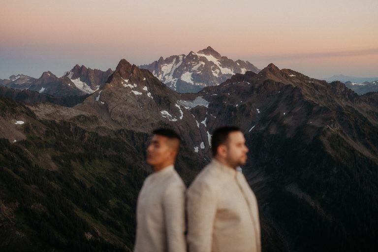 Two grooms stand back to back during their fire lookout elopement in the North Cascades.