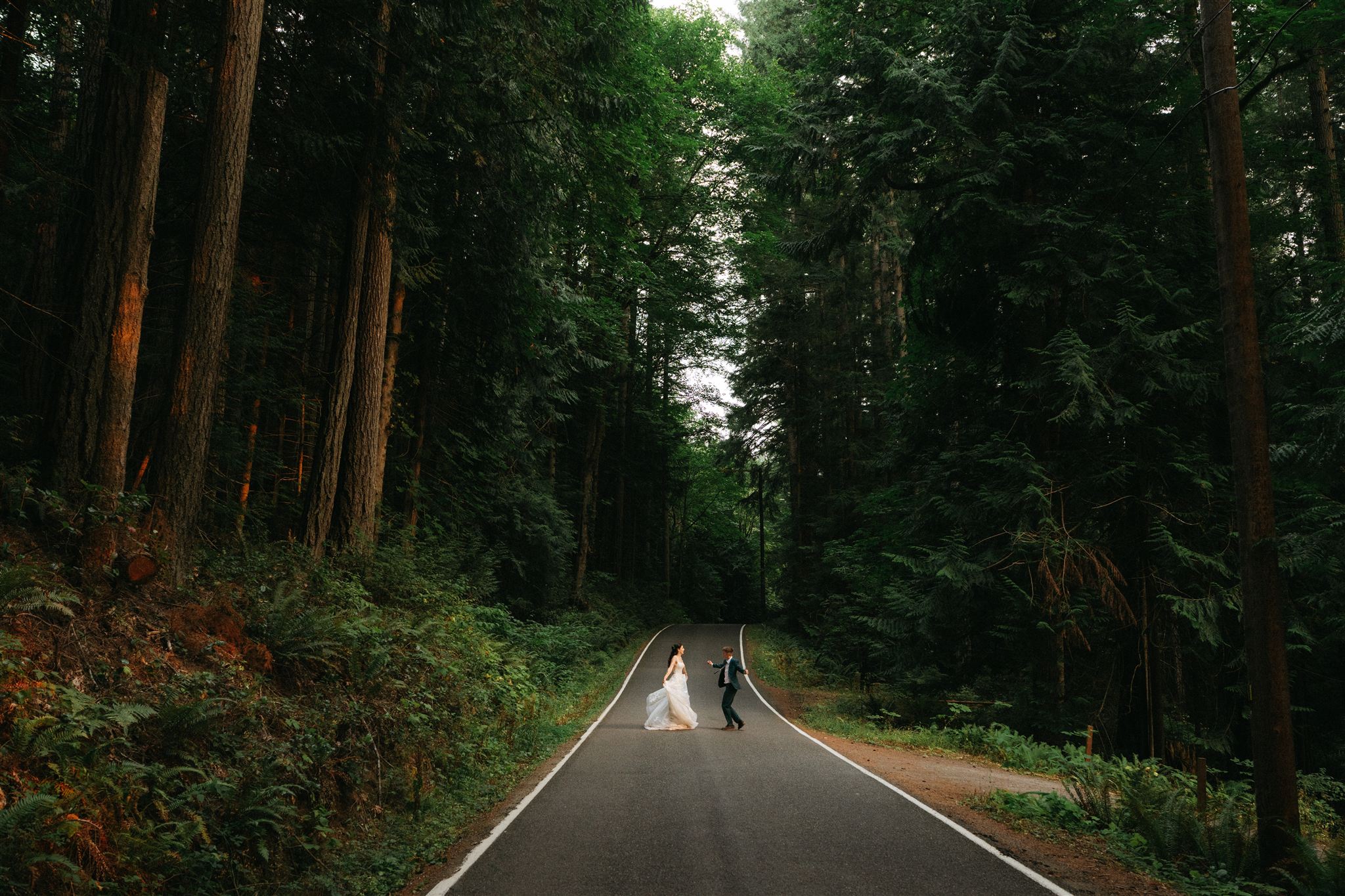 Brides dance on a road in the Olympic National Forest during their intimate forest wedding.