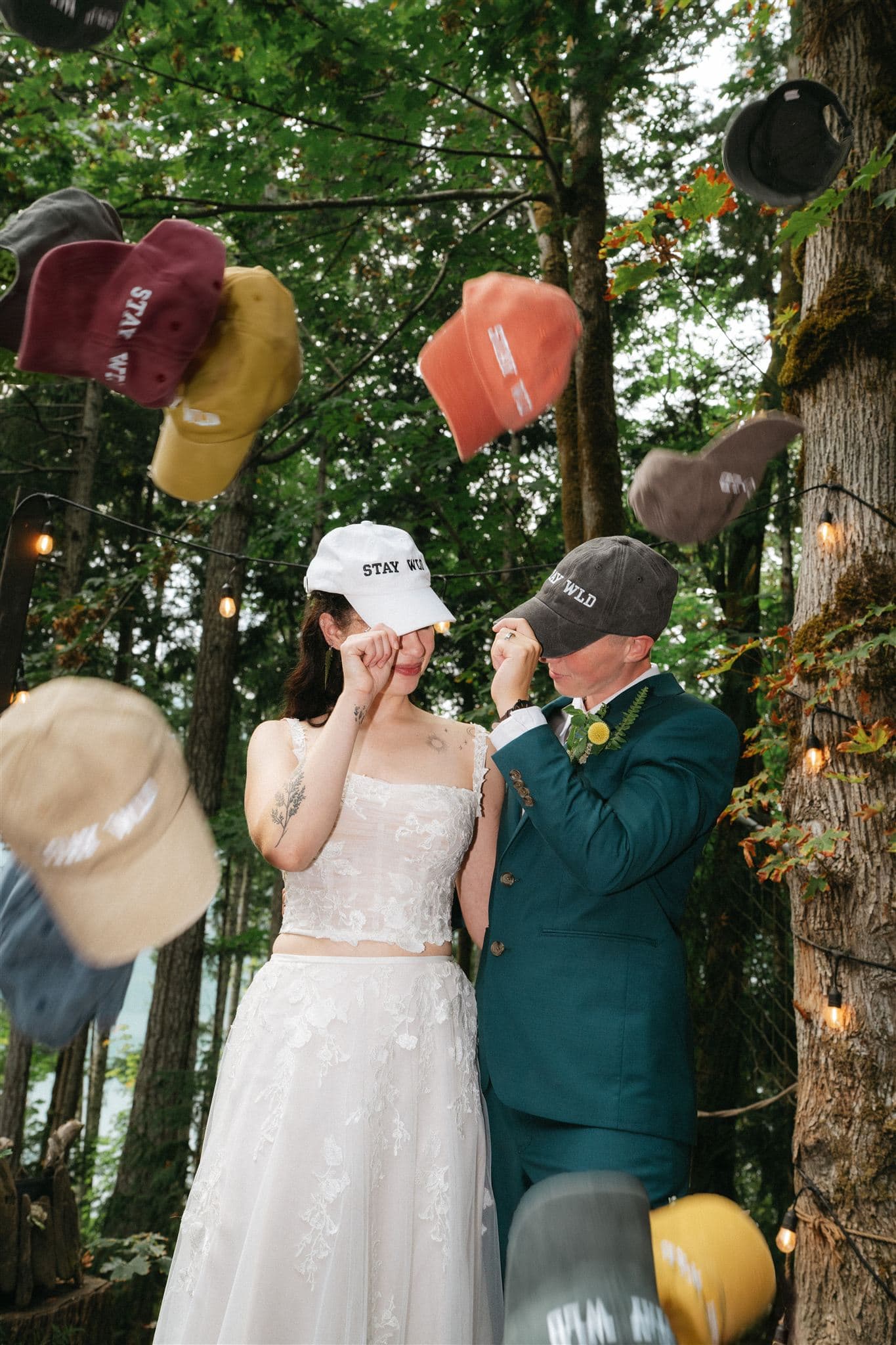 Brides wear matching "Stay Wild" hats at their forest elopement in Washington.